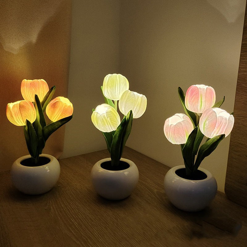 Three tulip lamps in orange, white, and pink on a wooden surface
