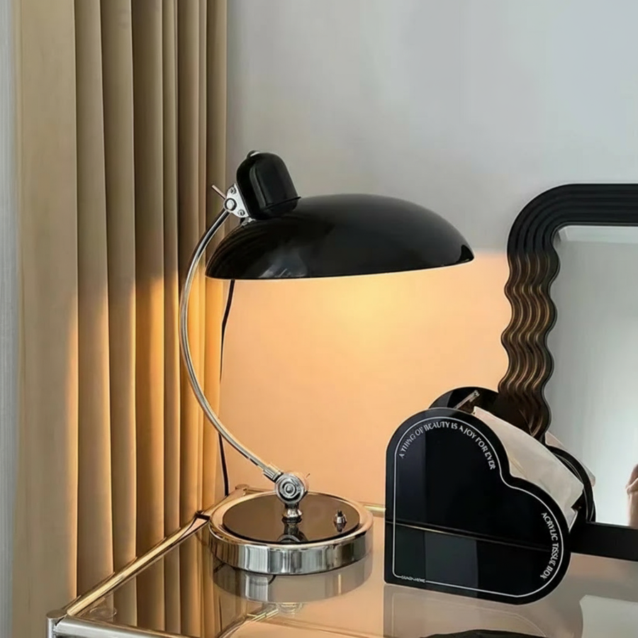 Desk lamp shown lit on a nightstand at dusk