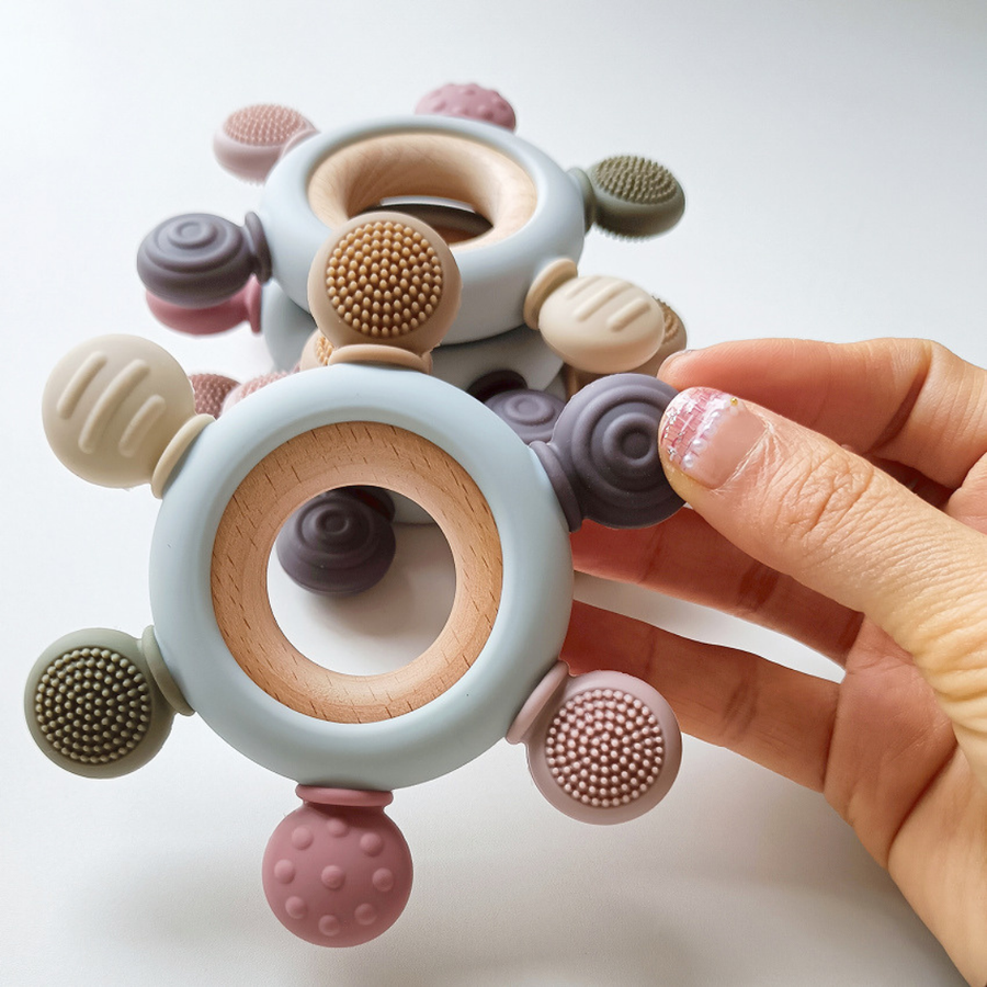Close-up of a silicone teething ring with a wooden ring attached.