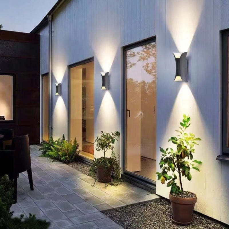 Outdoor LED wall light casting warm light on a garden wall