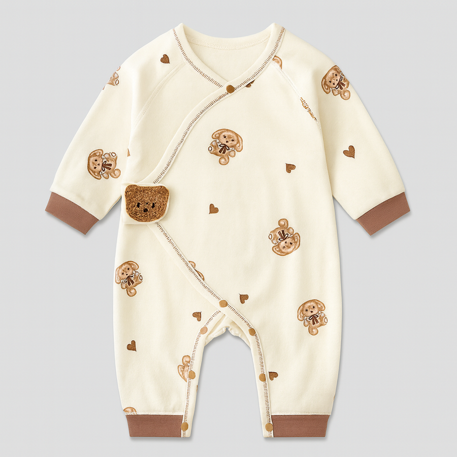 Cream-colored baby footie sleepsuit with brown bear print and crocheted bear applique