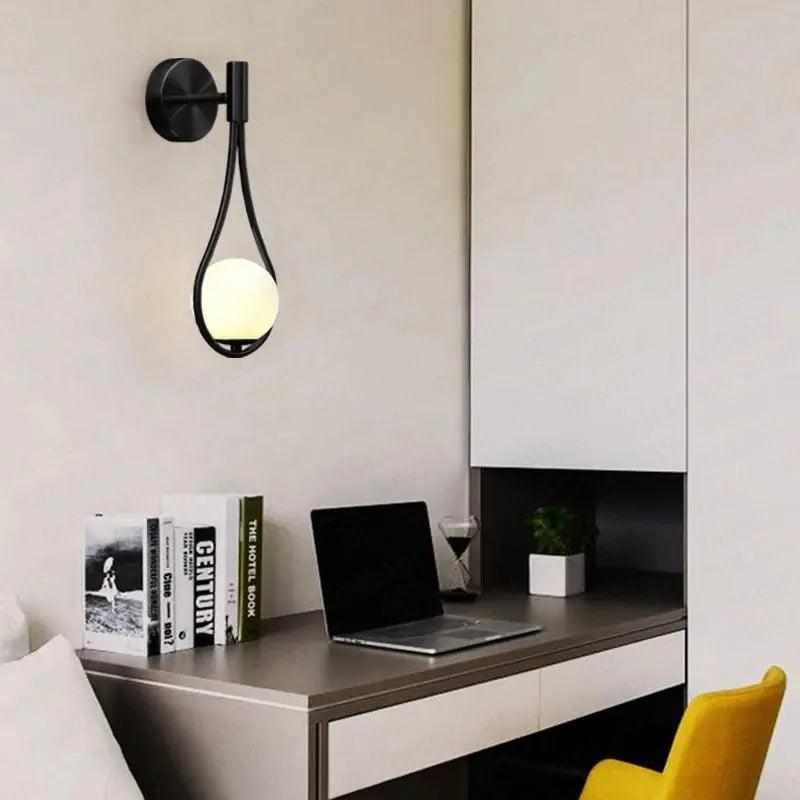 Gold wall sconce shown above a bedside table.