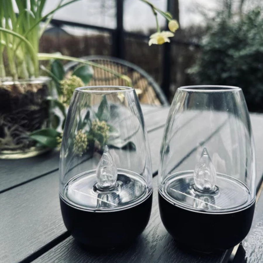 Two lanterns lit on an outdoor dining table during dinner.