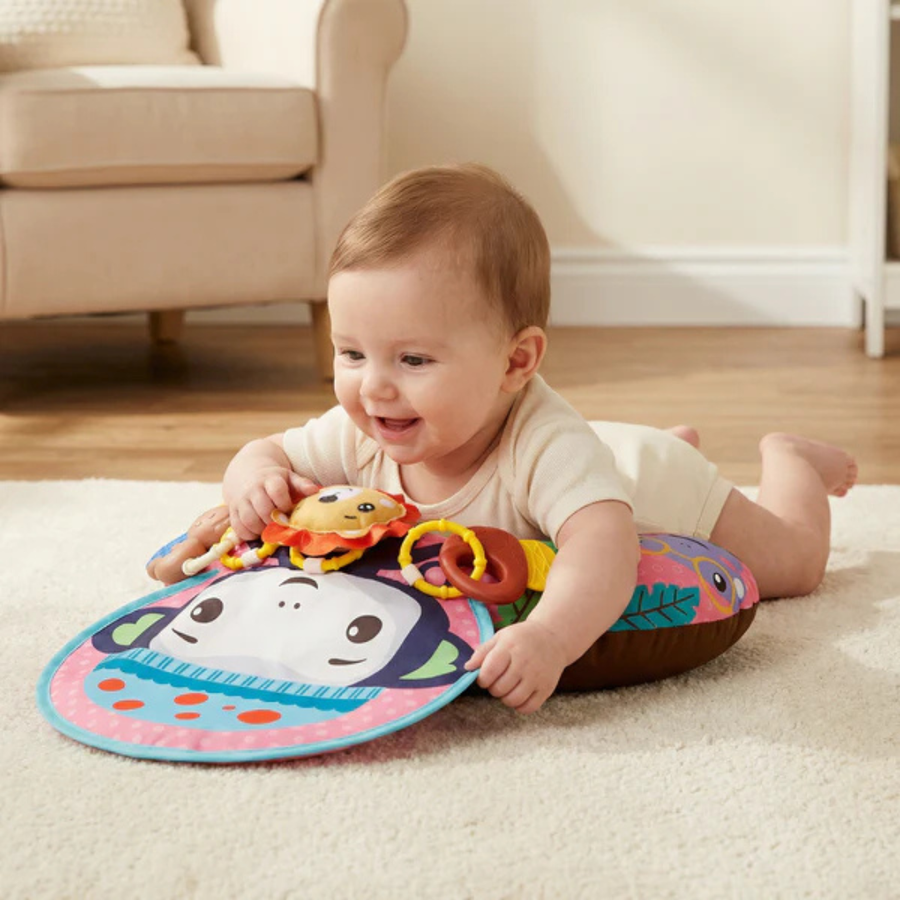 Baby reaching for a toy attached to the training pillow