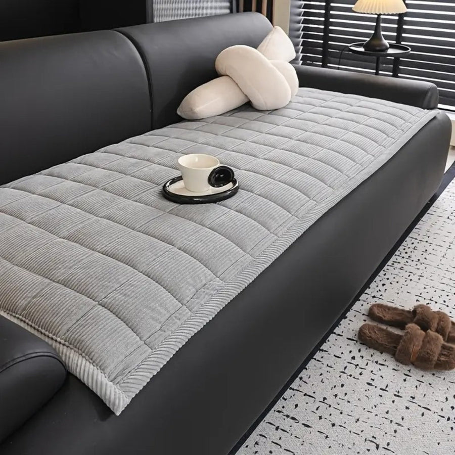 Quilted sofa cover shown in a living room setting