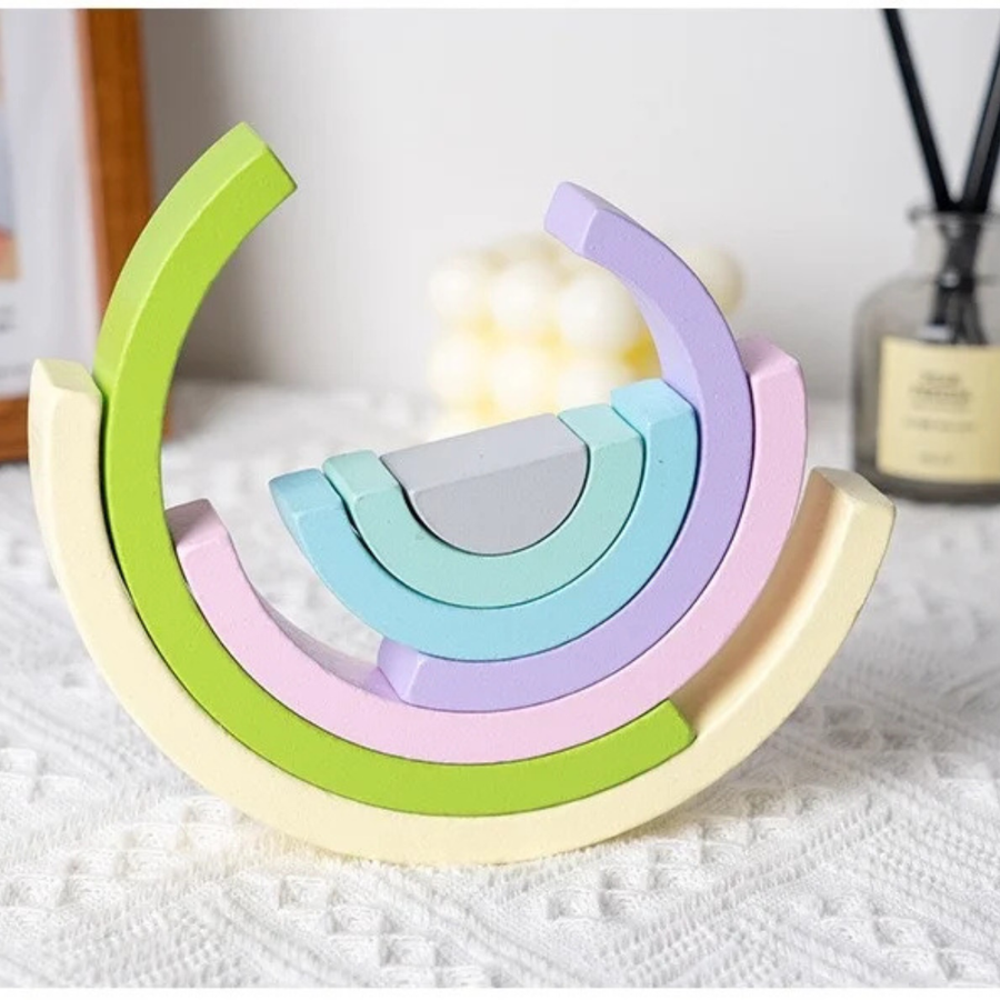 Child stacking rainbow-colored wooden arches during play.