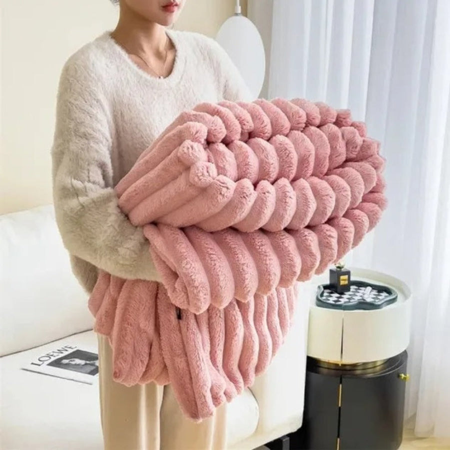 Fluffy warm blanket in ivory white on a couch corner