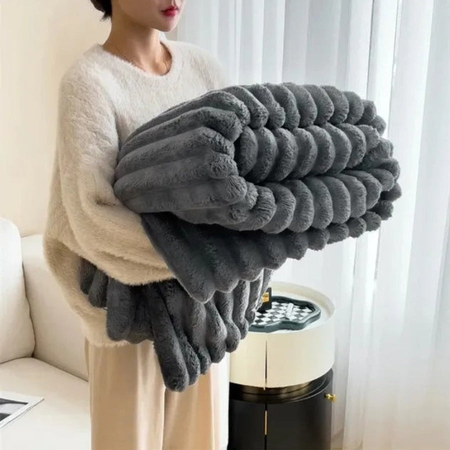 Fluffy warm blanket in charcoal gray on a sofa