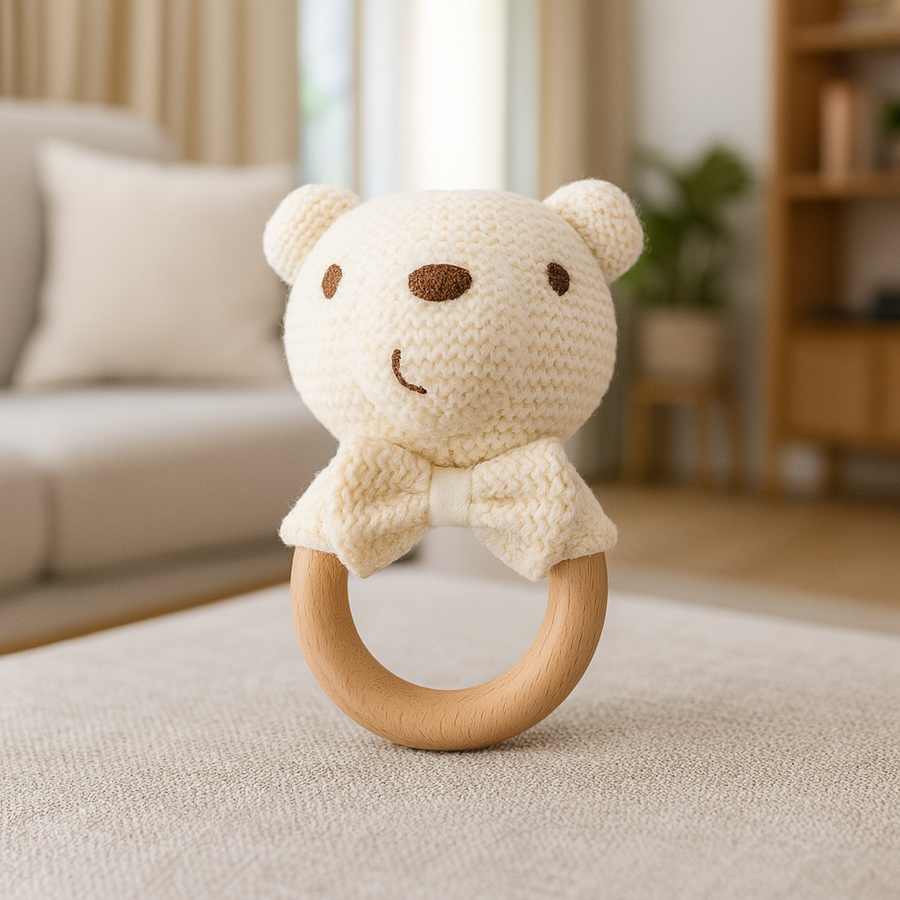 Cream-colored knit bear rattle with wood ring and soft bow
