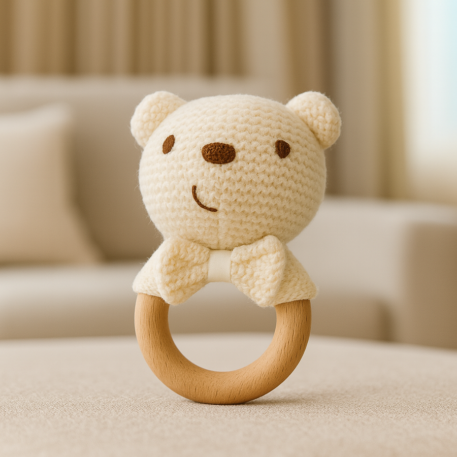 Cream-colored knit bear rattle with wood ring and soft bow