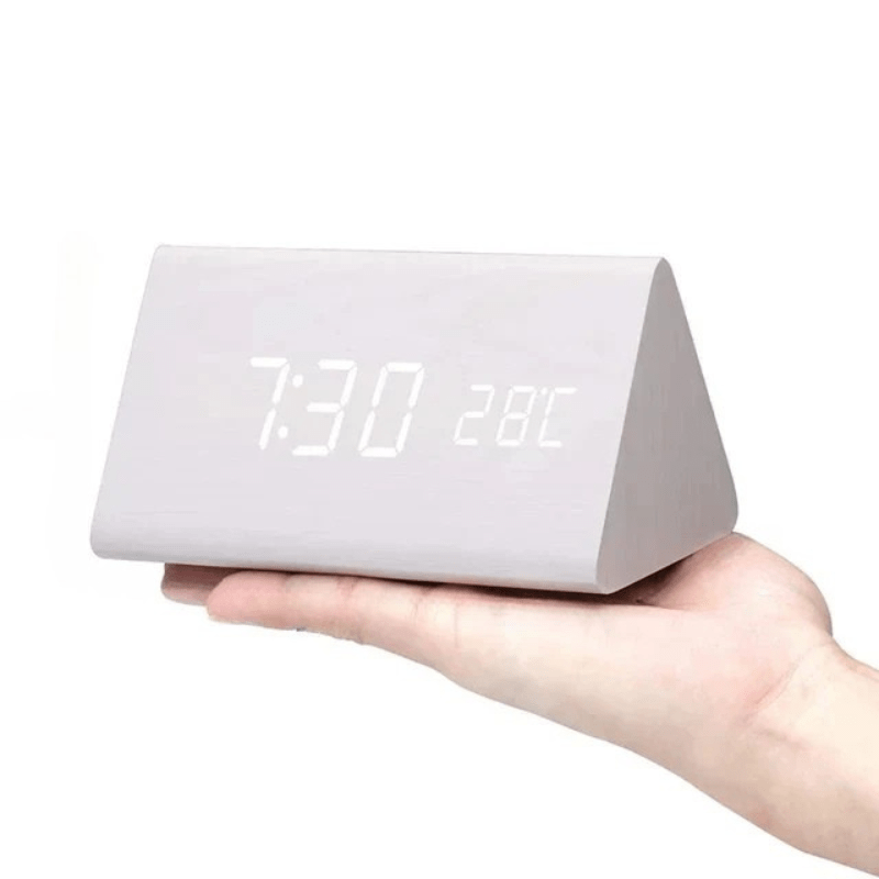 Triangular clock shown next to home decor items