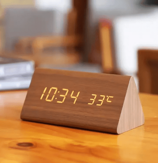 Triangular table clock with LED display on a wooden desk