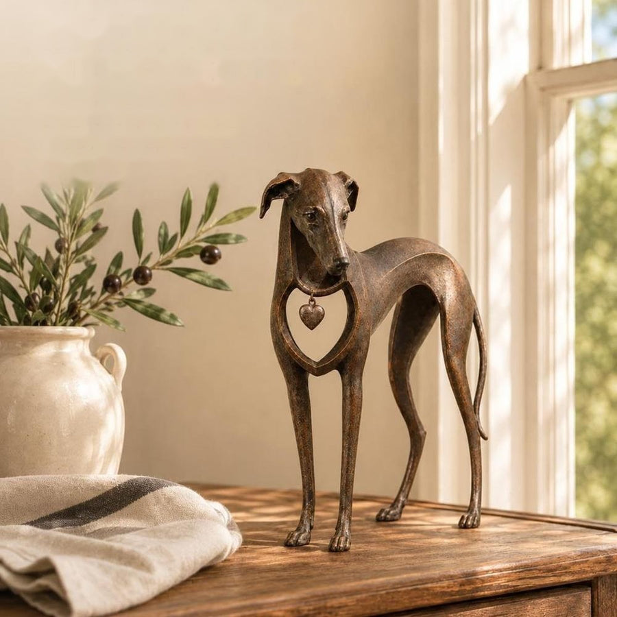 Greyhound figurine on wooden console beside olive branch and vase