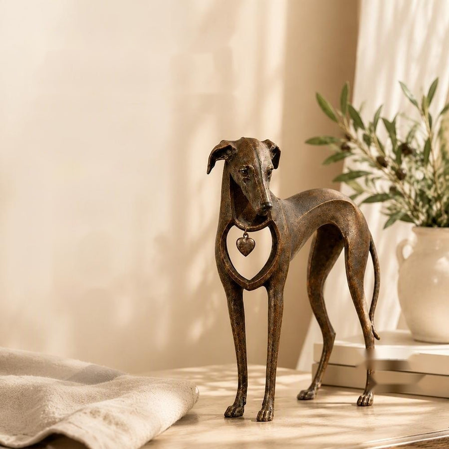 Sighthound sculpture on shelf with olive branch and stacked books