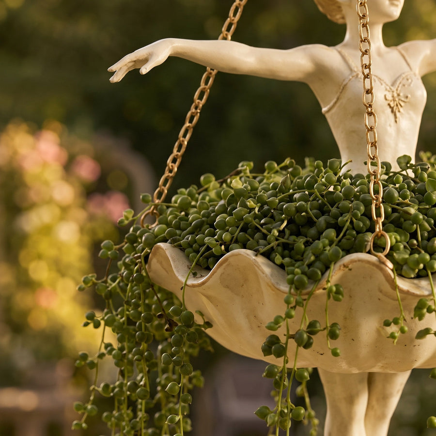 Close-up of the tutu pot with a trailing string-of-pearls plant and gold chains