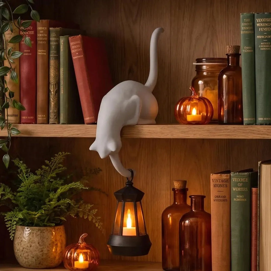 White cat figurine with hanging lantern on a bookshelf