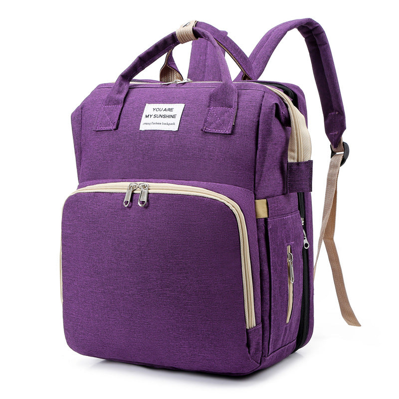 Diaper bag backpack open showing storage for diapers and wipes.