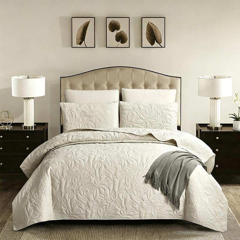 Beige embossed floral quilt set on a bed with matching pillow shams