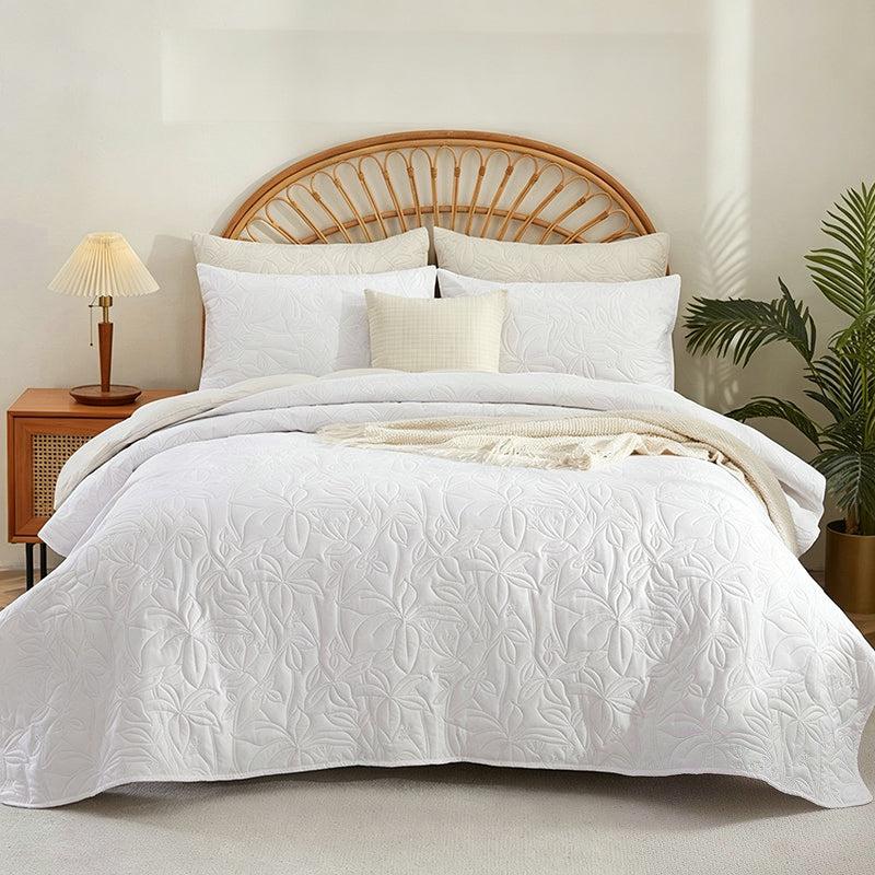 White quilted floral bedding set styled with a rattan headboard