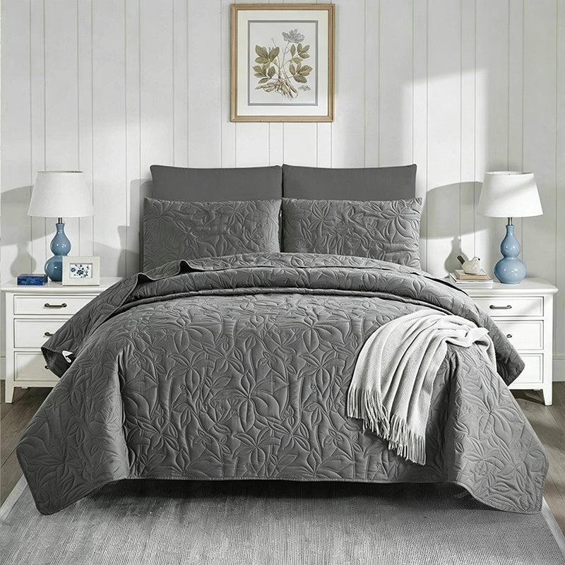 Gray quilted bedding set with striped pillowcases and throw blanket