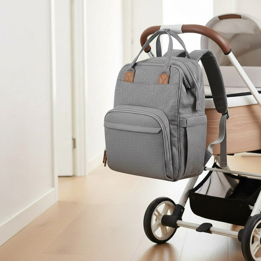 Gray diaper backpack hanging on a stroller in a hallway