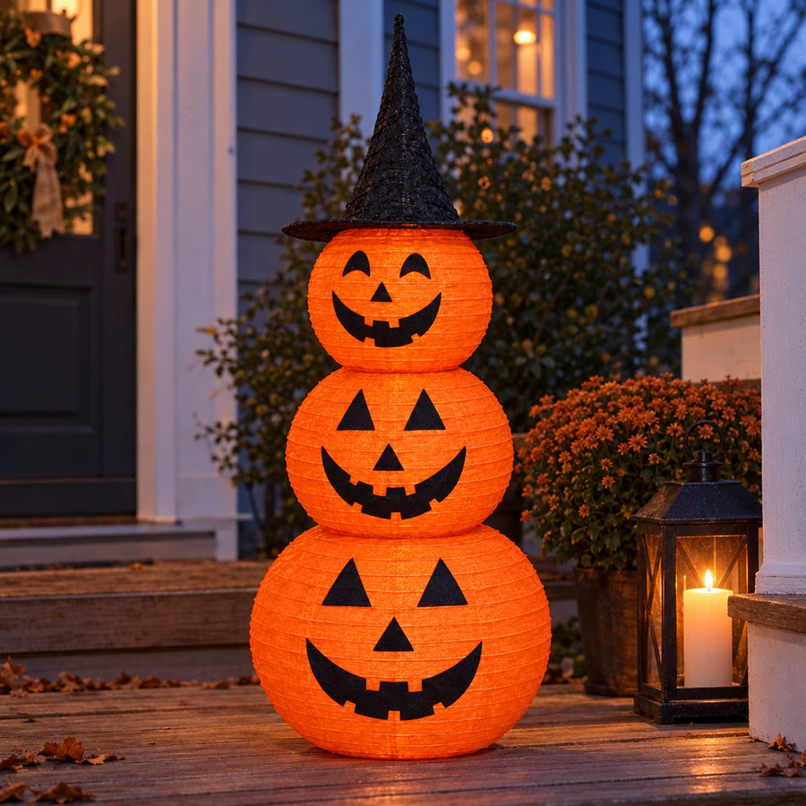 Pumpkin stack on dusk porch beside candle lantern