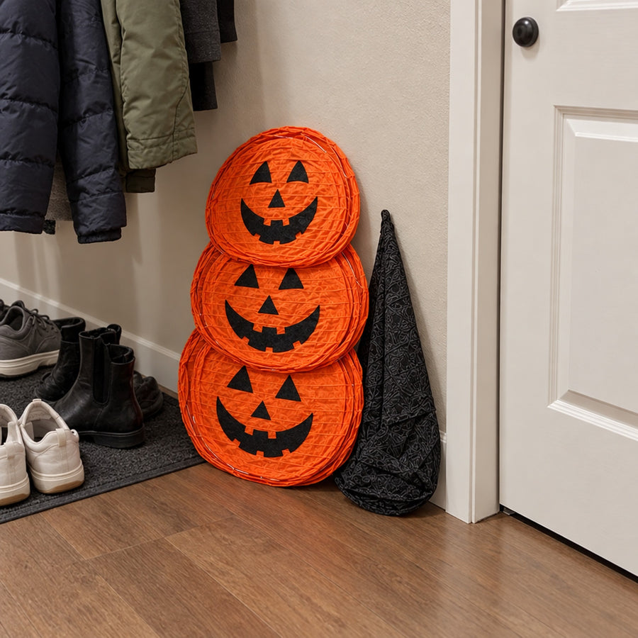 Flat-folded pumpkin decoration leaning in hallway by coats