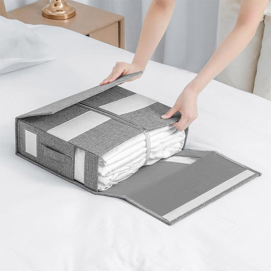 Gray folding bed sheet storage organizer on bed with hands closing lid