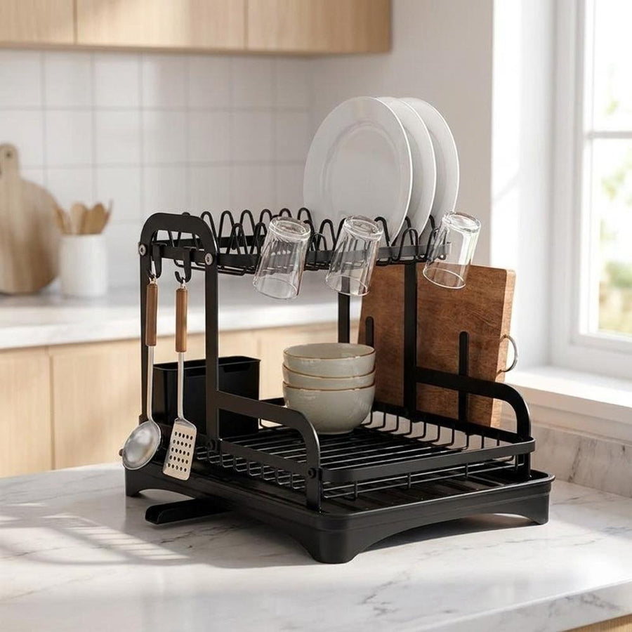 Dish rack with plates and glasses on marble kitchen countertop