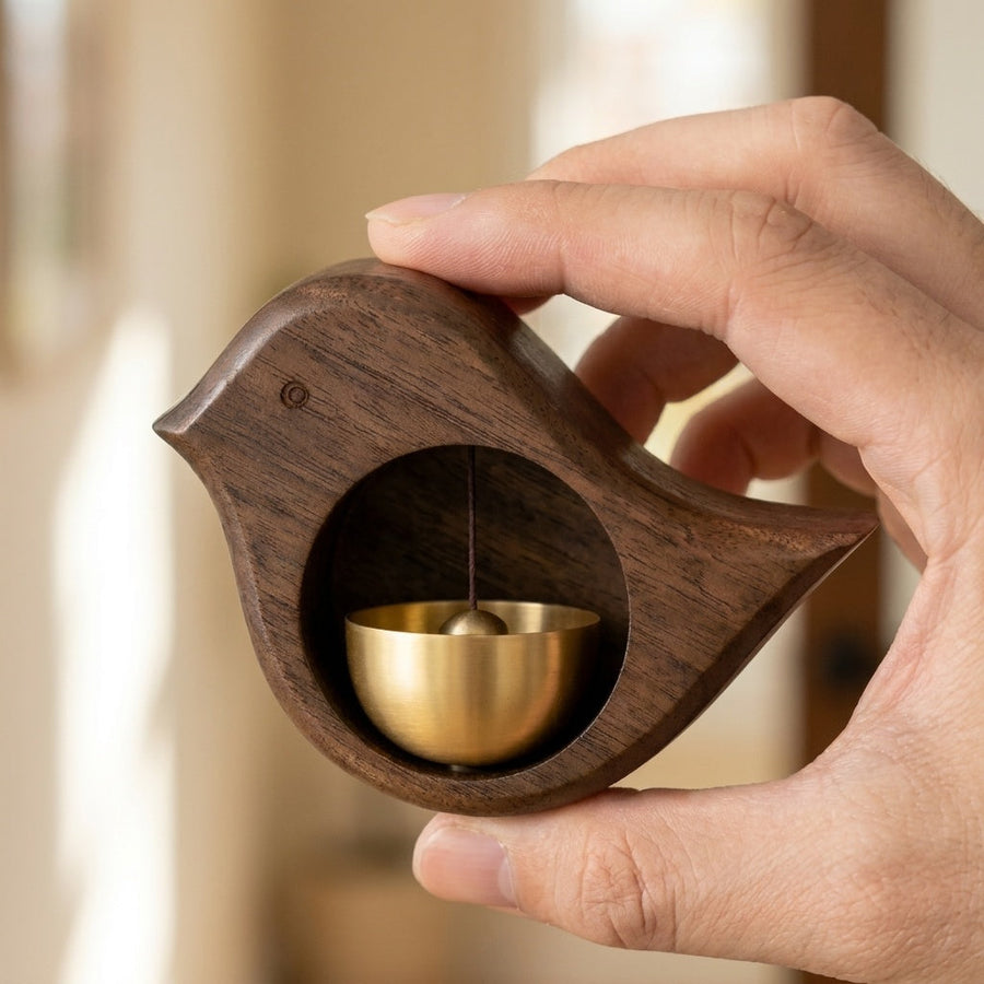 Bird-shaped door chime held in hands, brass bell visible