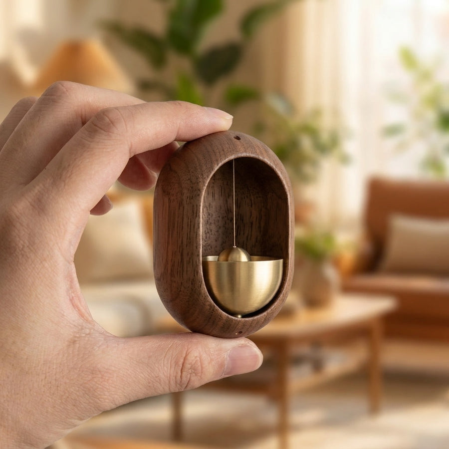 Oval door chime held in hand, showing brass bell and clapper