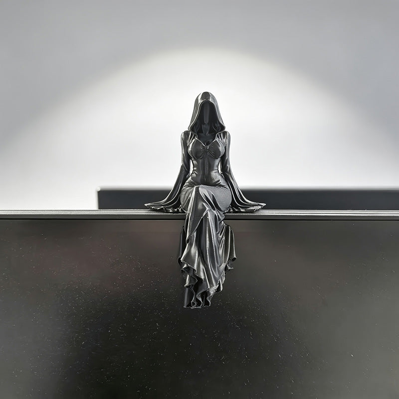 Gothic shelf-sitter statue on a monitor, black hooded figure