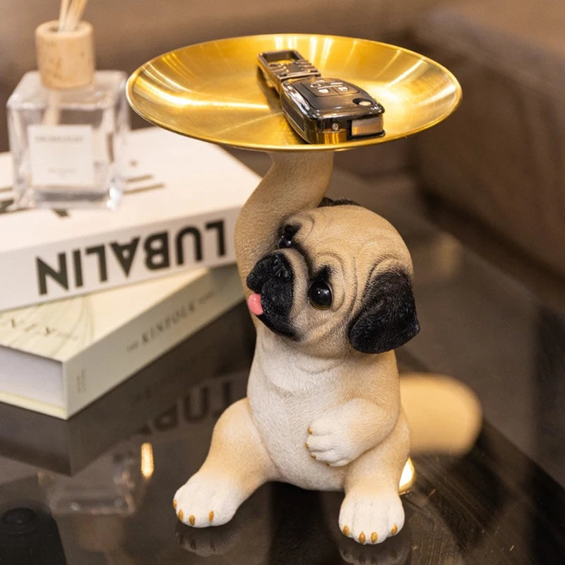 Pug figurine with a gold tray holding a car key on a glass table