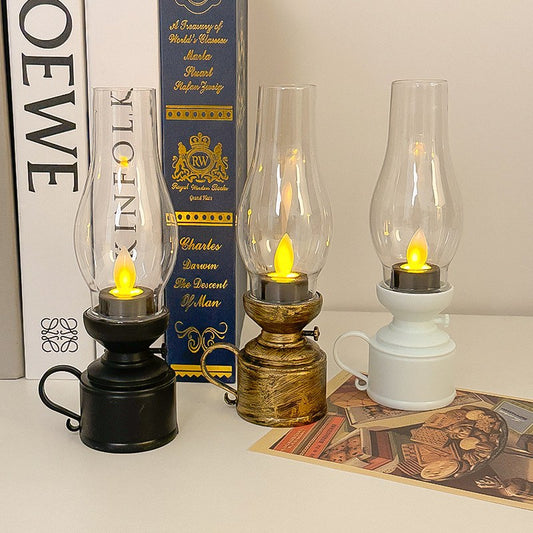 Three vintage LED oil lamps in bronze, black, and white on shelf
