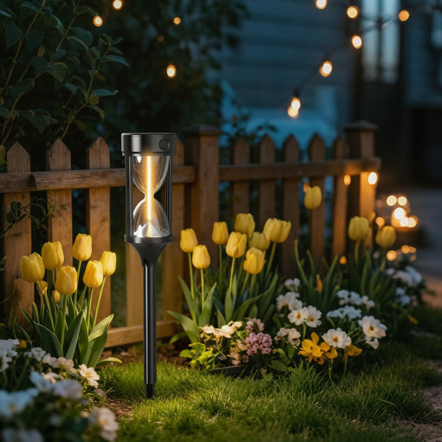 Hourglass solar garden light among tulips