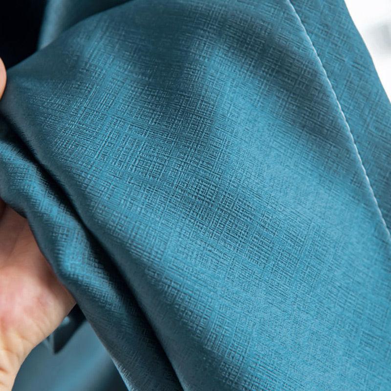 Close-up fabric texture of teal blackout curtain showing woven material