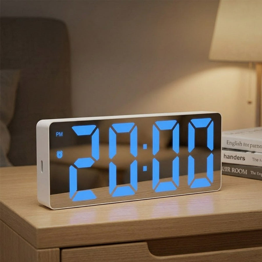 Digital alarm clock with a white case and blue LED display on a shelf