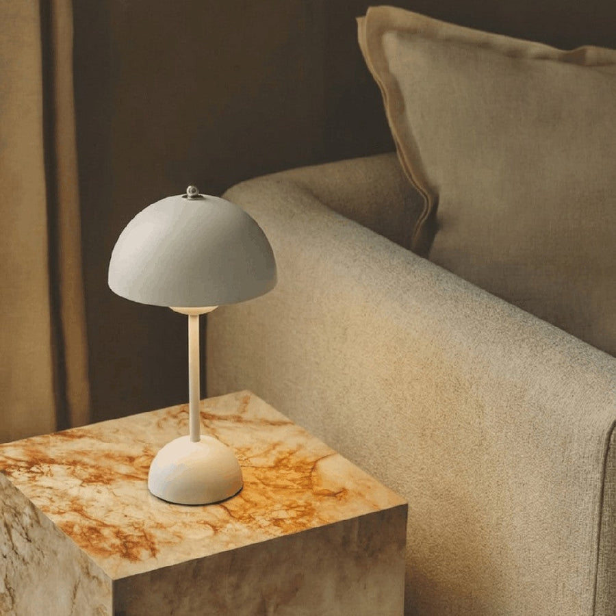 Rechargeable gray table lamp on a marble table next to a sofa
