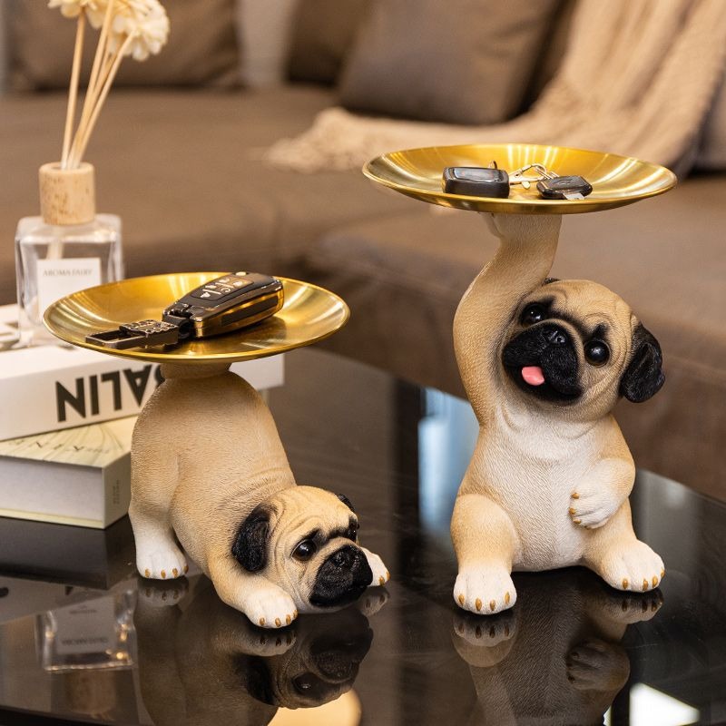 Two pug statues with gold trays shown in different poses
