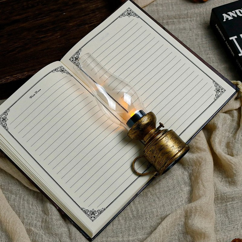 Bronze vintage oil lamp glowing on open journal book