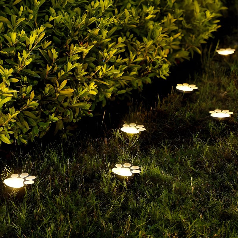 A row of glowing paw-shaped solar lights along a garden path