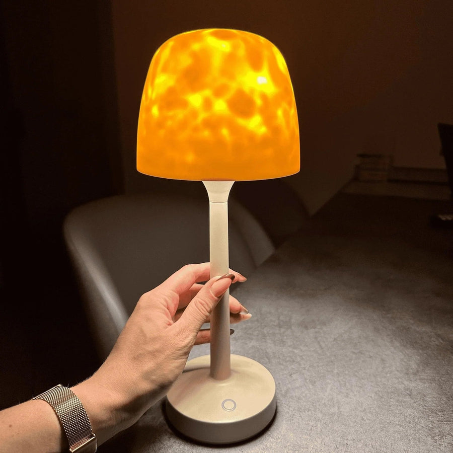 A hand holding the table lamp with aurora projection