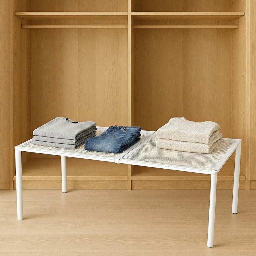 Expandable steel closet shelf holding jeans and sweaters against a light background