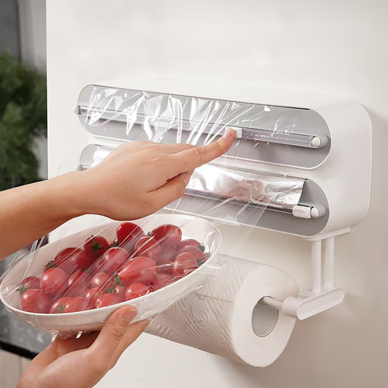 Hand pulling aluminum foil from the dispenser mounted on a wall