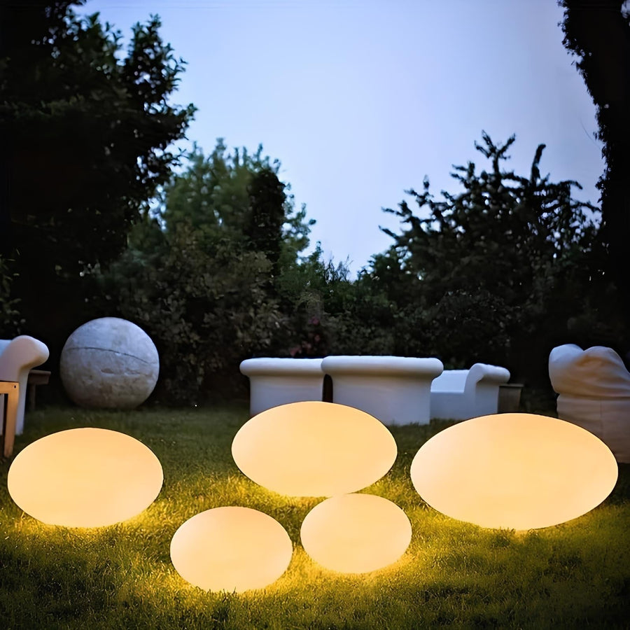 Glowing stone-shaped garden lamps on the lawn at dusk