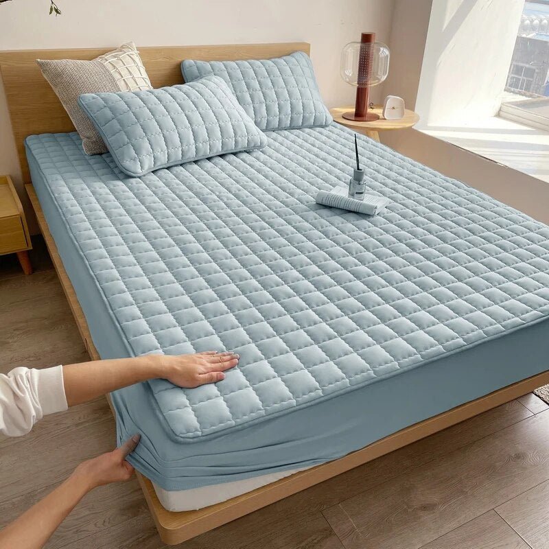 Quilted mattress cover in beige tone on a bed