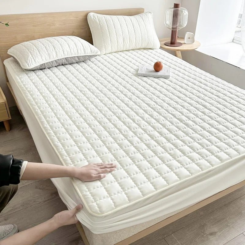 Quilted mattress cover shown on a neatly made bed