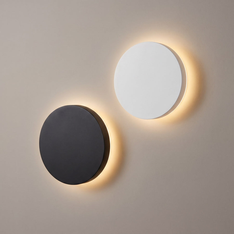 Black and white round LED wall lights both lit from behind