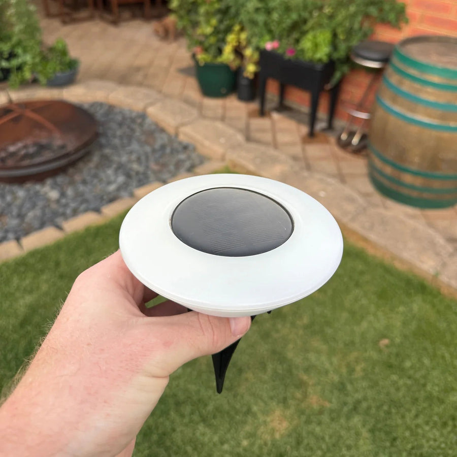 Hand holding a solar ground light showing the ground spike