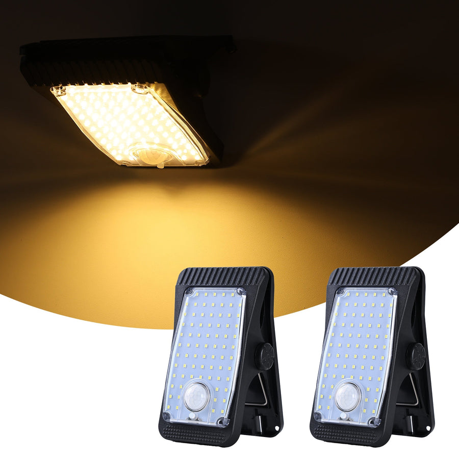 Two solar lights with clip mounts glowing warm white